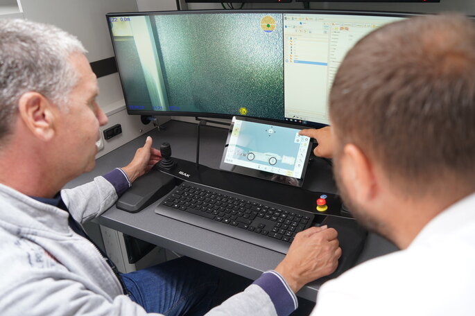 Marco Marold erklärt einem Teilnehmer des "Workshops on the road 2024" das Bediensystem BS10X im Fahrzeug