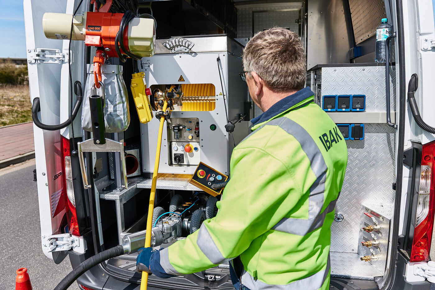 Aufnahme eines Bedieners am Fahrzeugheck bei der Bedienung der Fräsroboterwinde