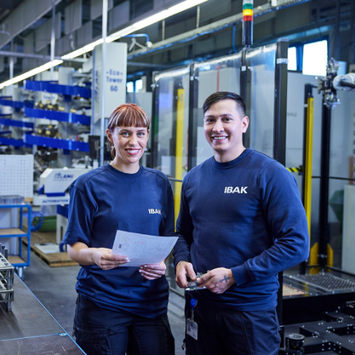 Julia Köster und Jan Hollm in der Fertigungshalle vor den CNC-Maschinen